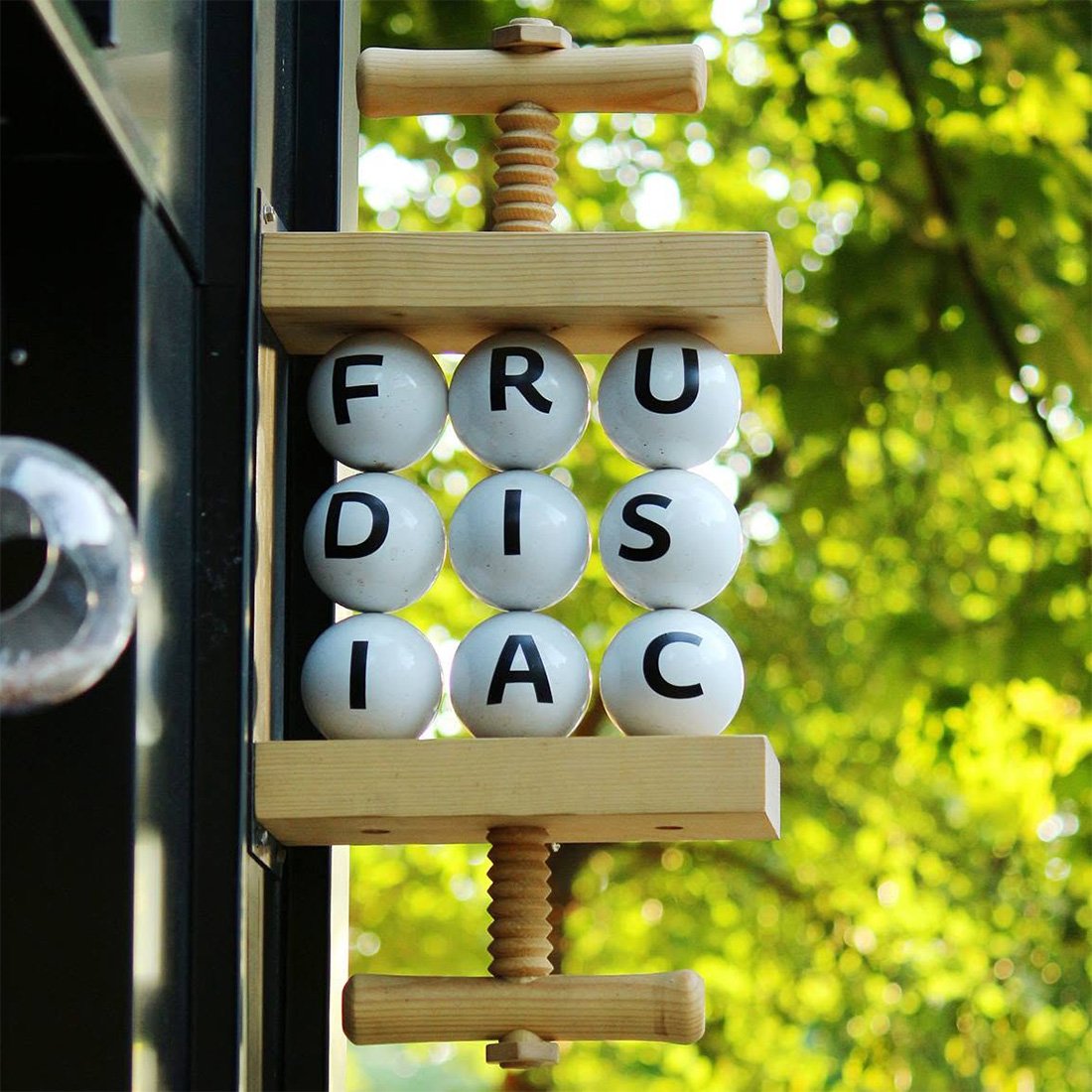 Frudisiac hanging blade sign with white lettered balls in wooden fruit press — signage by Brandient
